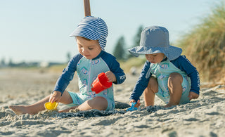 Baby boys under umbrella at the beach wearing UPF50+ Swimwear.