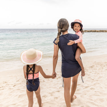 Girl wearing ditsy coral swimsuit at beach.