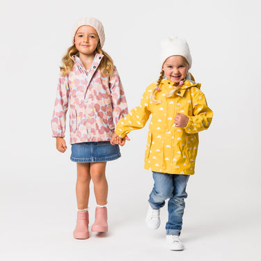 Two girls holding hands wearing Snapper Rock raincoats.