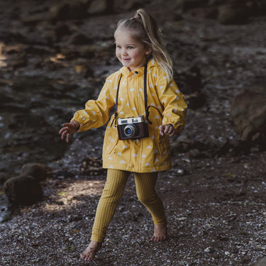 Girl wearing bright yellow raincoat for kids, with camera.