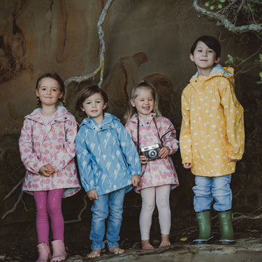 Children wearing pink, blue, and yellow Snapper Rock raincoats.